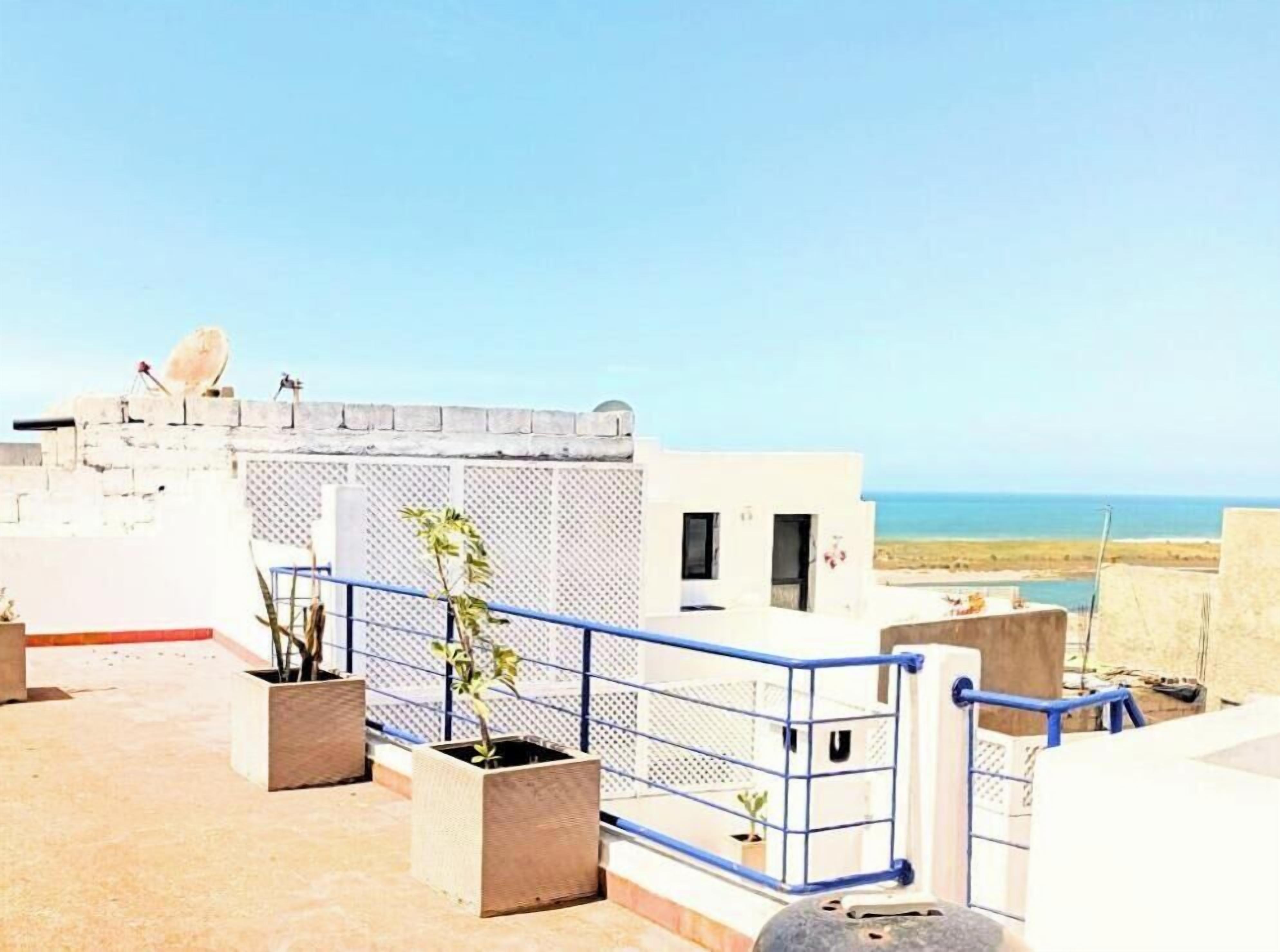 A rooftop terrace with a clear view of the sea, a satellite dish, and potted plants.