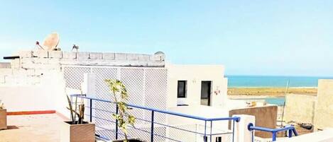 Una terraza en la azotea con vistas despejadas al mar, una antena parabólica y plantas en macetas.