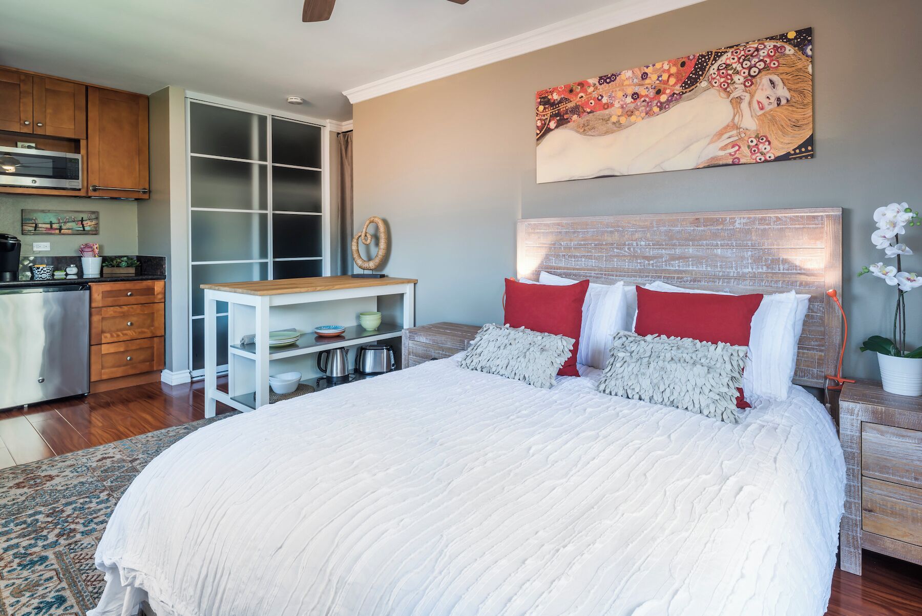 A bedroom with a large bed, a wooden headboard, and a painting above it.