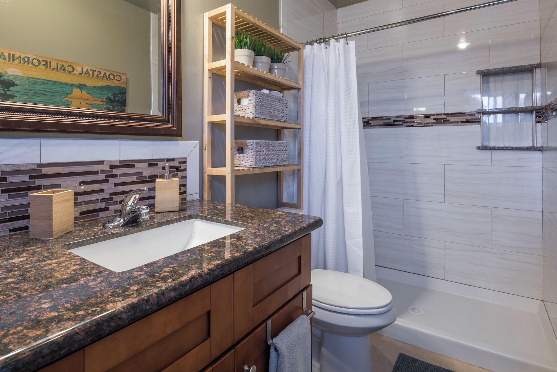 A bathroom with a granite countertop sink, wooden cabinets, a toilet, and a shower area with a glass enclosure.