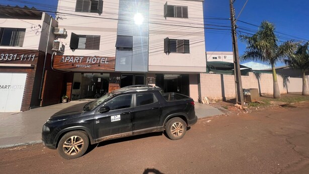 A two-story building with a sign for 'APART HOTEL' and a parked car in front. - apart hotel ijui (Ijuí)