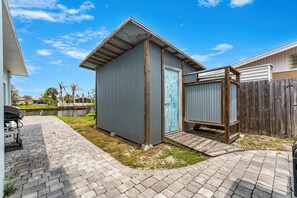 A backyard with a metal shed, a wooden deck, and a paved walkway.