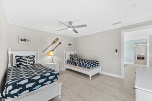 A bedroom with two beds, a ceiling fan, and a nightstand with a lamp.