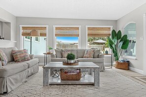 A living room with a sofa, a coffee table, and a large plant.