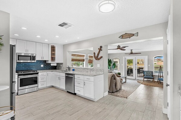 A modern kitchen with white cabinetry, a built-in microwave, and a stainless steel oven.