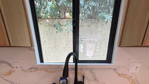 Uma cozinha com uma pia dupla, uma janela acima da pia e vista para o exterior.