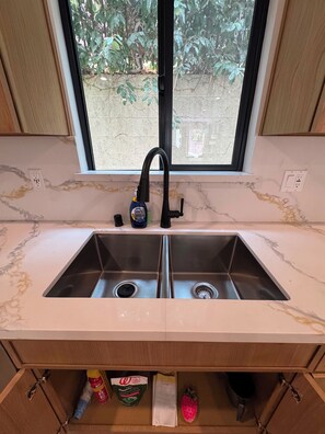 A kitchen with a double sink, a window above the sink, and a view of the outside. - Modern 2 bedroom + 2 bath - 10 mins to Rodeo drive and attractions (Beverly Hills)