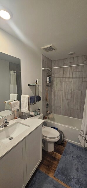 A modern bathroom with a sink, mirror, toilet, shower, and bathtub. - 3-bedroom house in peaceful Fort Myers near Lehigh Acres with AC comfort (Fort Myers)