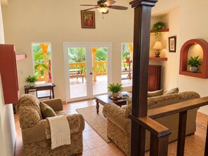 A living room with two sofas, a coffee table, and a ceiling fan. There are doors leading to an outdoor area with a balcony. - Beautiful 3-bedroom country house with AC in Bocas del Toro (Bocas del Toro)