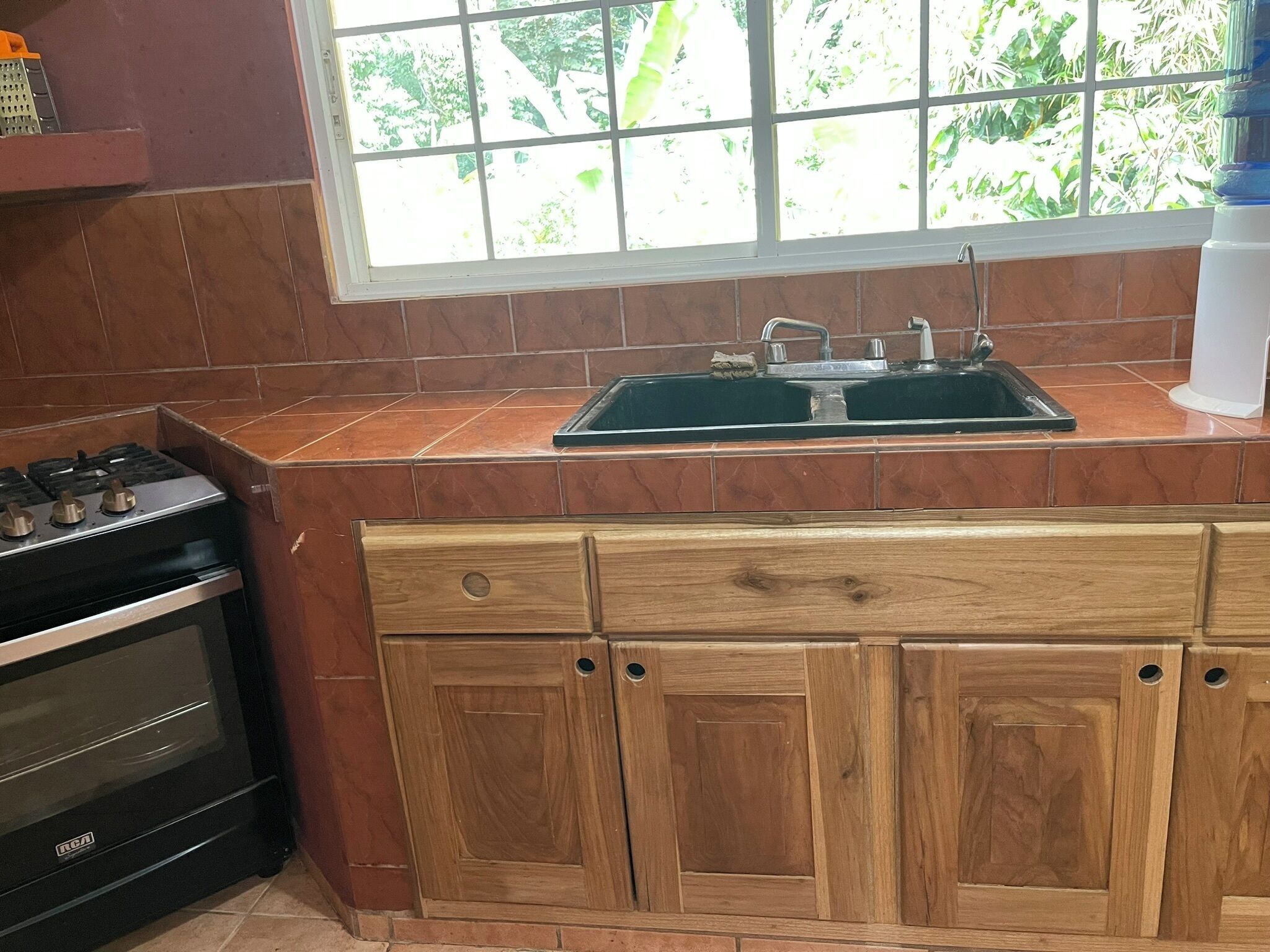 A kitchen with a stove, sink, and wooden cabinets.