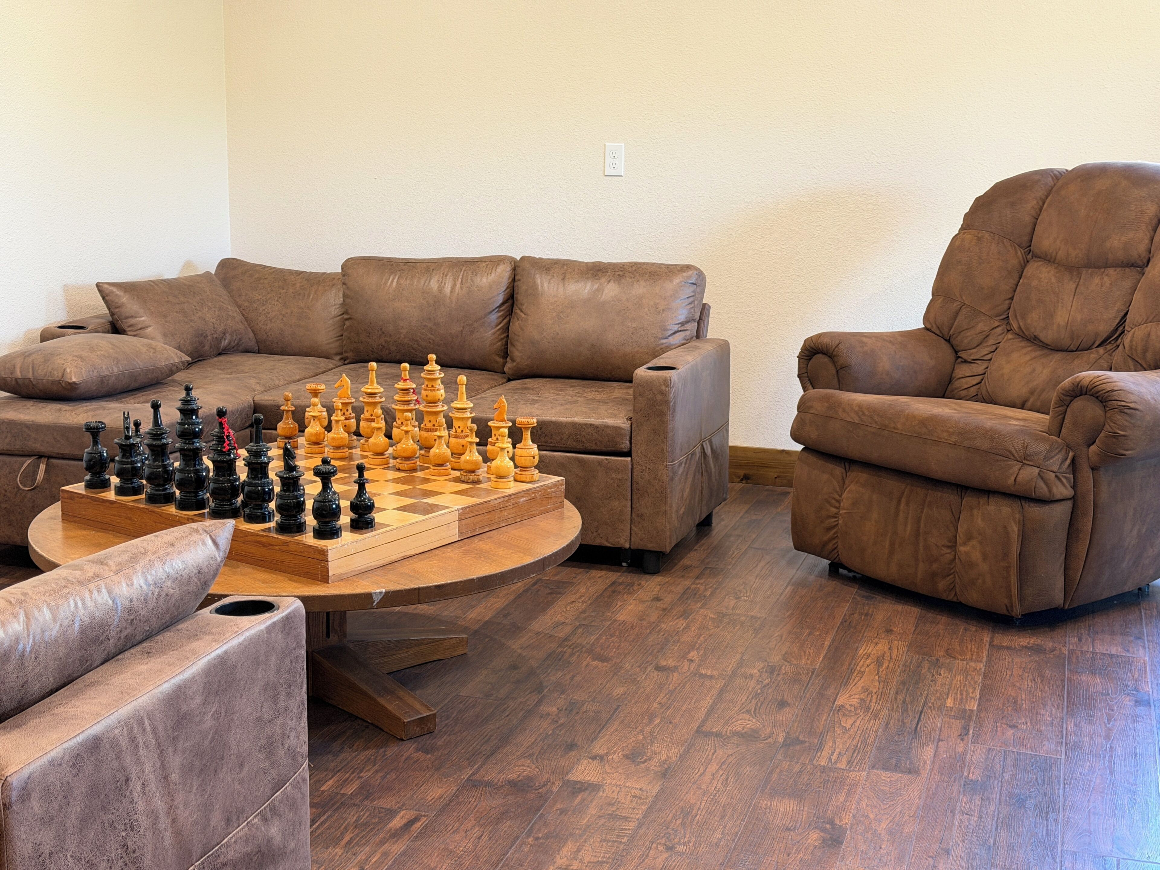 A living room with a chessboard, two sofas, and a recliner.