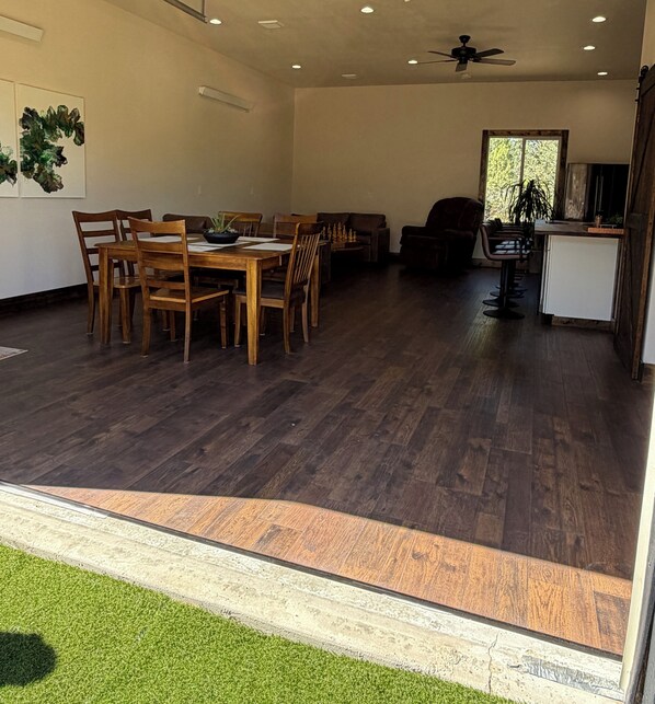 A spacious living area with a dining table, chairs, a sofa, and a kitchen area with a bar.