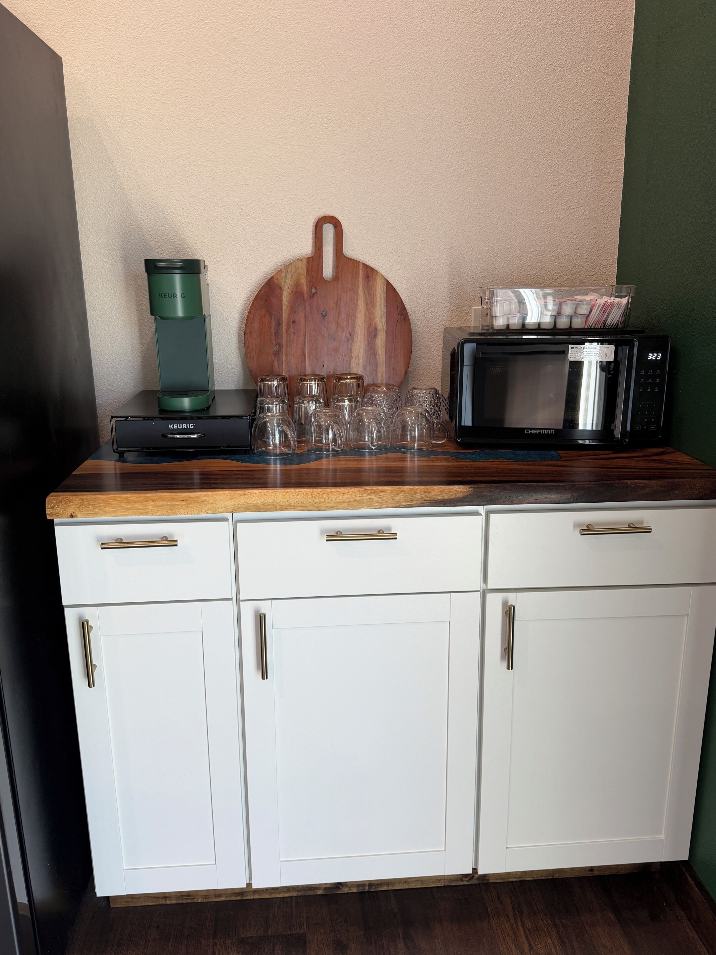 A kitchenette with a coffee maker, microwave, and glassware.