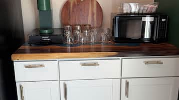 A kitchenette with a coffee maker, microwave, and glassware.