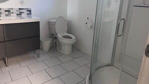Een badkamer met toilet, wastafel, spiegel en douchecabine.