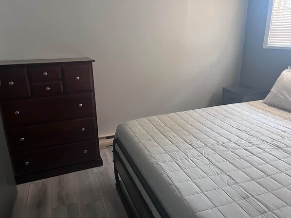 A bedroom with a bed, a dresser, and a nightstand.