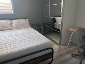 Un dormitorio con cama, escritorio y armario.