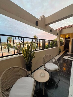 A balcony with two wicker chairs and a small table, a potted plant, and a view of the cityscape. - Casa Palam 2 (La Paz)
