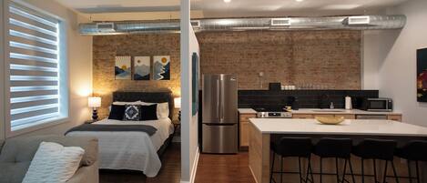 A modern apartment with a bedroom, kitchenette, and a dining area.