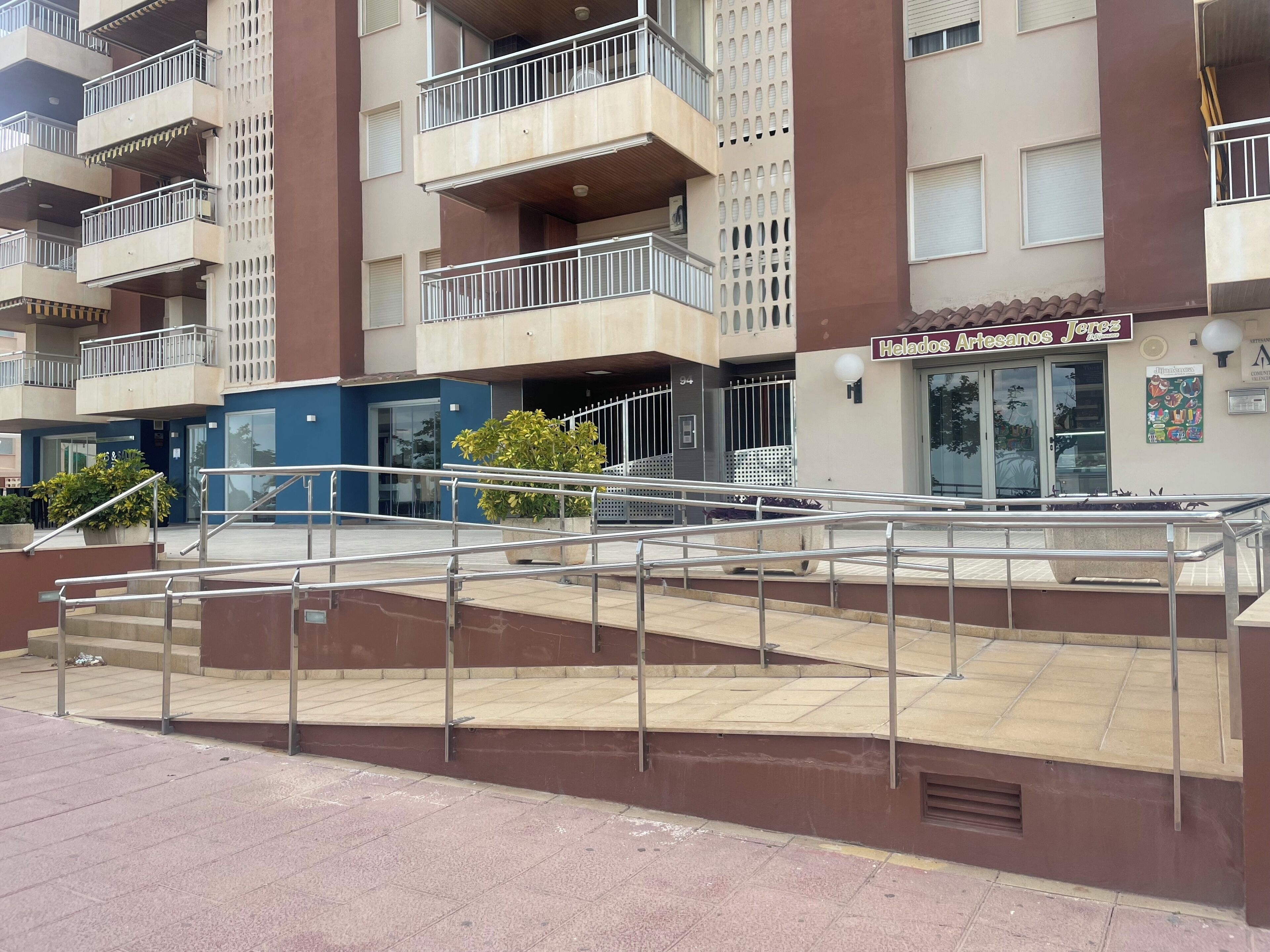 A multi-story residential building with balconies, a staircase, and a storefront named 'Helados Artesanos Jerez.'