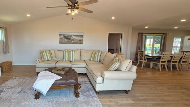 A spacious living room with a large sectional sofa, a wooden coffee table, and a ceiling fan. - Luxury Lakeview Home with Panoramic Views. Sleeps 10 (Golden)