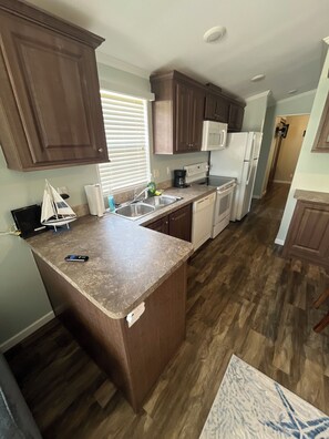 A kitchen with wooden cabinets, a microwave, a refrigerator, and a dishwasher. - Snowbird Retreat in Beautiful Bradenton Florida! (Bradenton)