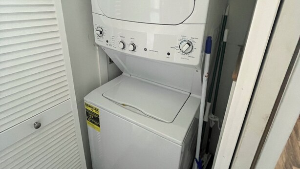 Uma lavanderia pequena e compacta, com máquina de lavar e secadora embutidas, um armário de armazenamento e uma porta com ripas horizontais.