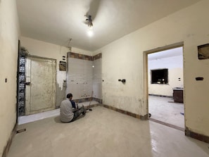 Una habitación con piso de baldosas, una puerta con celosía metálica y un ventilador de techo.