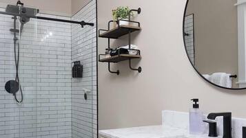 Een badkamer met een douchecabine van glas, een toilet, een wastafel met spiegel en een wasbak.