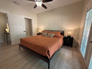 A bedroom with a bed, two bedside tables, a ceiling fan, and a window.