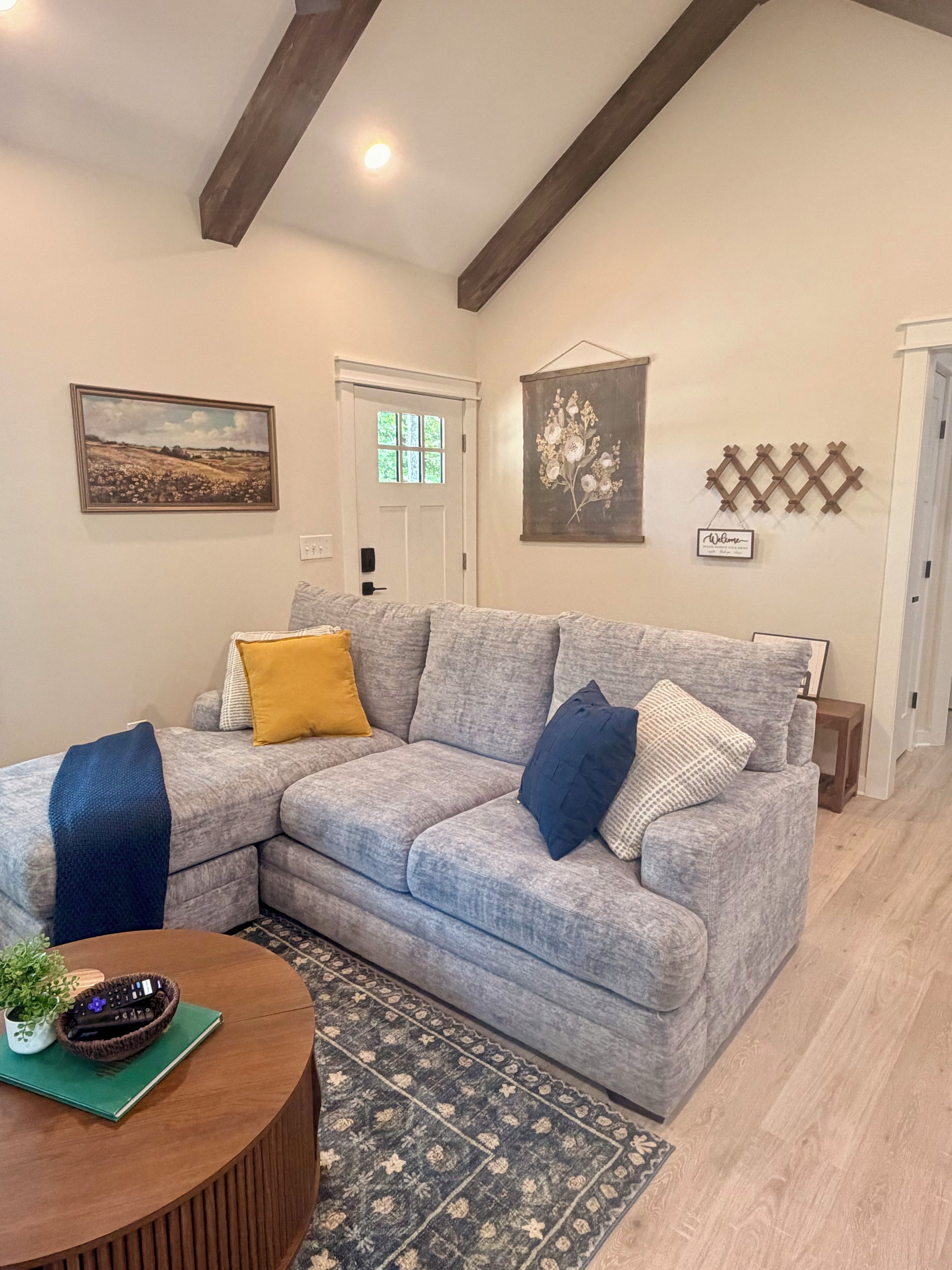 A living room with a sectional sofa, a coffee table, a rug, and wall decor.