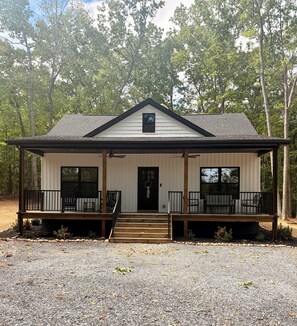 A two-story building with a front porch, a central door, and a small window above the door.