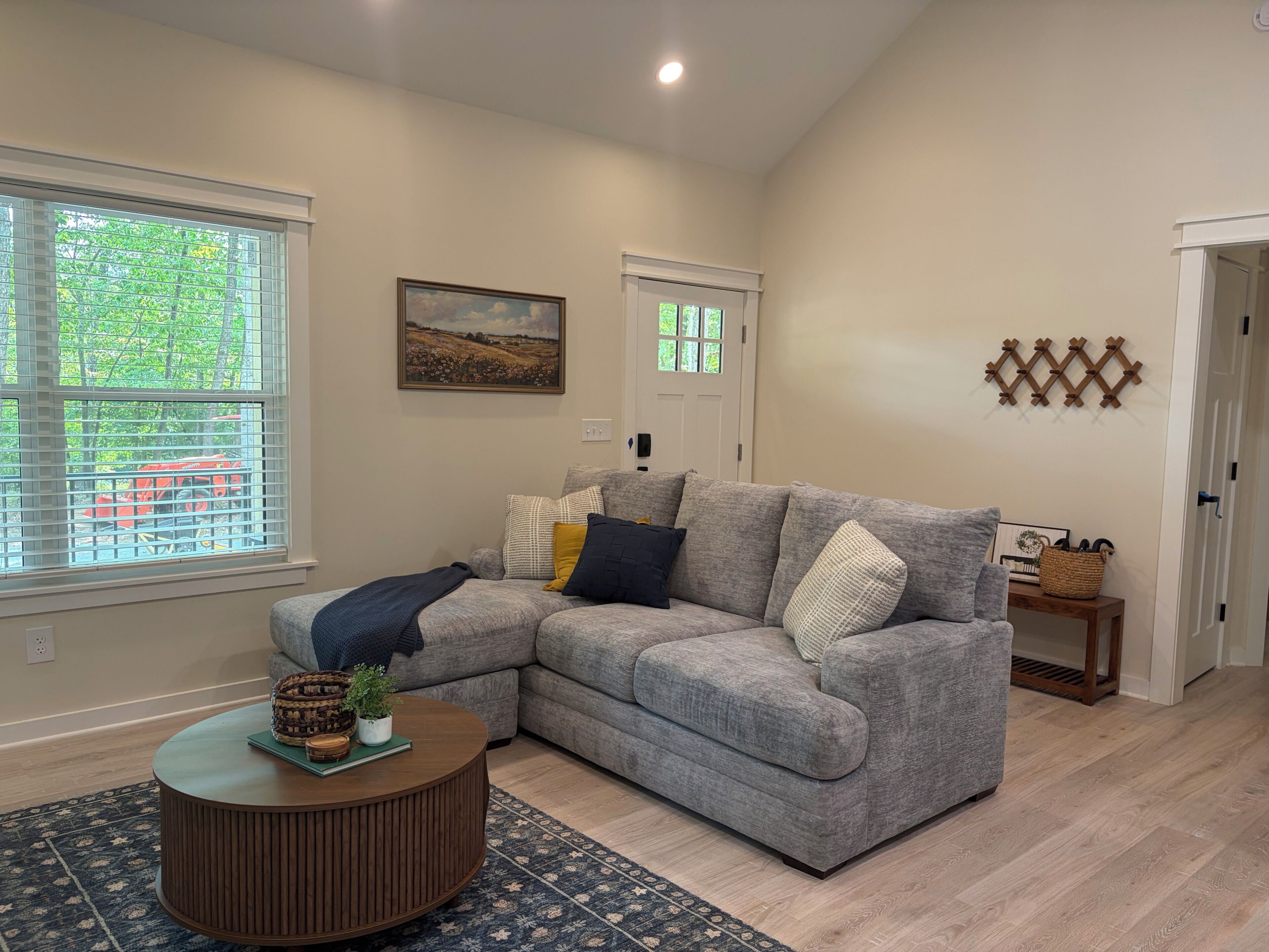 A living room with a sectional sofa, a round coffee table, and a patterned rug.