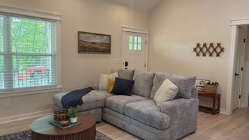 A living room with a sectional sofa, a round coffee table, and a patterned rug.
