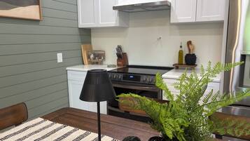 A modern kitchen with white cabinets, a stainless steel range, and a black floor lamp.