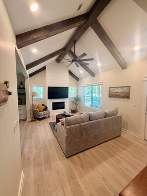 A spacious living room with a fireplace, a large sofa, and a ceiling fan.