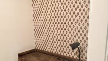 Un espacio de trabajo en esquina con un escritorio de madera, una silla negra y una lámpara de escritorio.