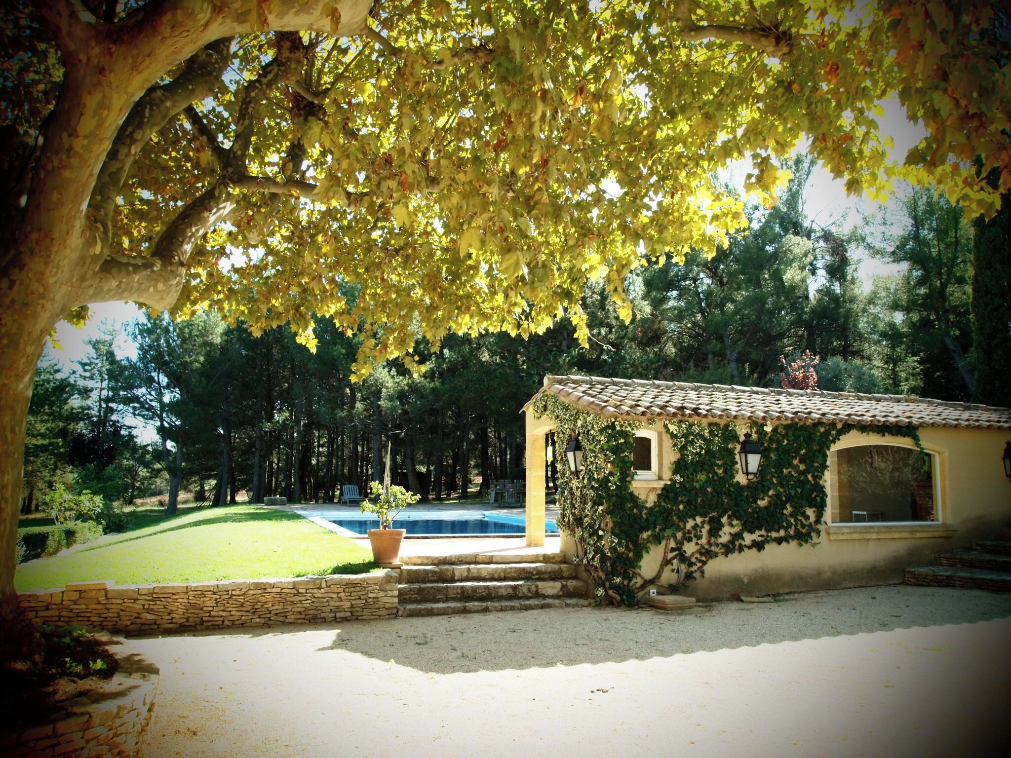 A villa with a swimming pool, stone walls, and a garden.