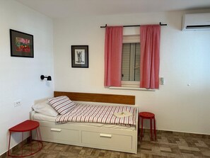 A bedroom with a bed, two red stools, a window with red curtains, and wall-mounted artwork. - LACI2 - an apartment with terrace for 4 people (Krk)