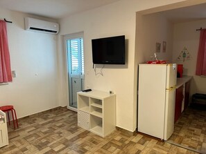 A compact kitchen with a white refrigerator, a mounted TV, and a window with blinds. - LACI2 - an apartment with terrace for 4 people (Krk)