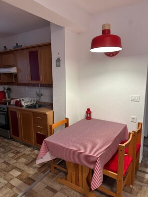 A dining area with a table set for two, wooden chairs, a red lantern, and a red pendant light. - LACI2 - an apartment with terrace for 4 people (Krk)