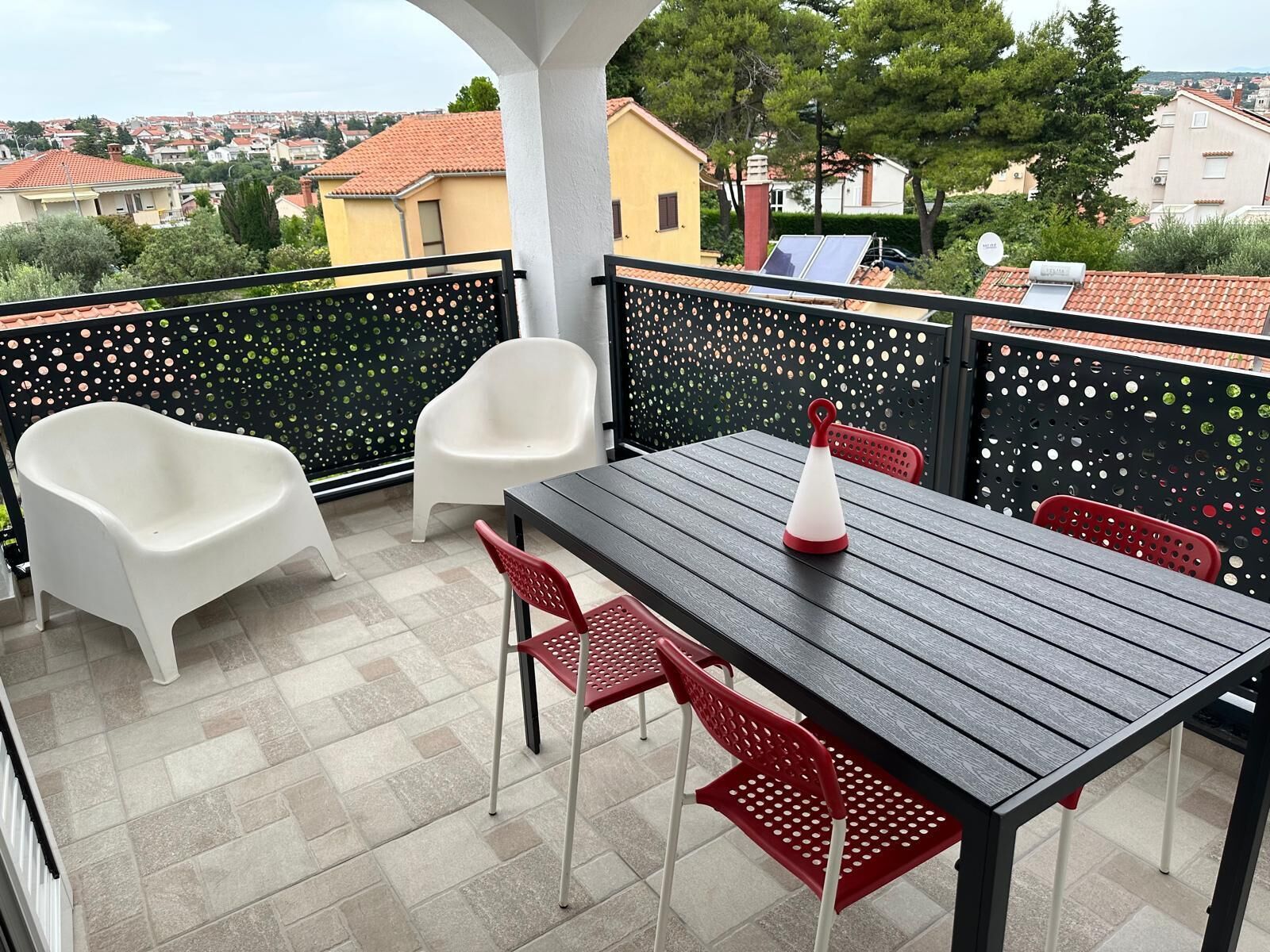 Ein Balkon mit Tisch und Stühlen, einer weißen Badewanne und Blick auf die Stadt.