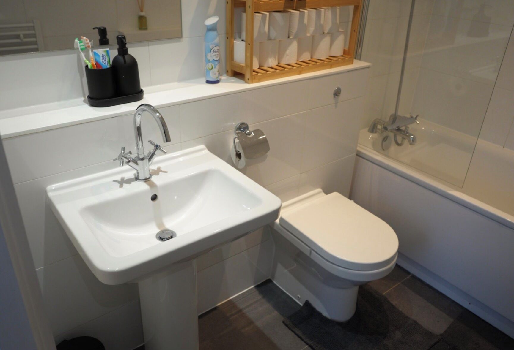 Ein Badezimmer mit einem weißen Waschbecken, einer Toilette und einer Duschkabine.