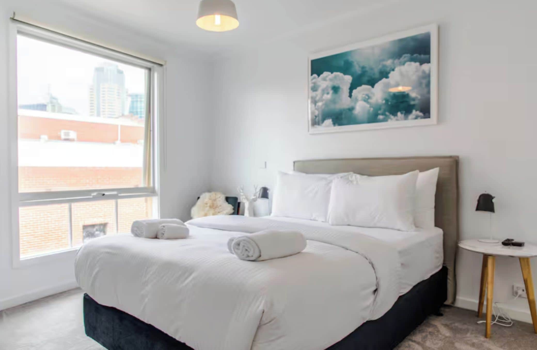 Een hotelkamer met een groot bed, uitzicht op de stad en een schilderij aan de muur.