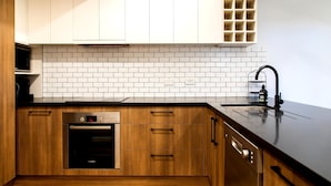 Cozinha moderna com armários brancos, painel de backsplash de tijolos e forno Bosch.