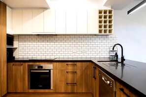 Eine moderne Küche mit weißen Schränken, einer Ziegelrückwand und einem Backofen von Bosch.