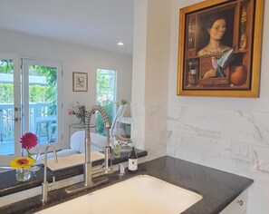 Eine moderne Küche mit doppelter Spüle, Edelstahlarmatur und Marmor-Spritzschutz.