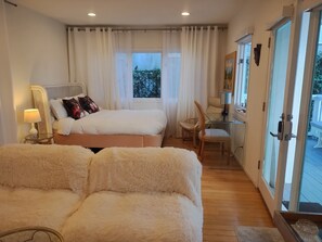 A bedroom with a bed, a chair, a desk, and a view of the outdoors. - Venice Canals Beach House (Los Angeles)