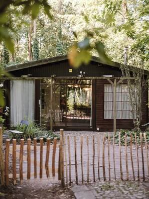 A wooden cabin with a porch, surrounded by trees and a wooden fence. - A cozy chalet nestled among the tall trees and birds. Pet-friendly! Great location! (Lanaken)