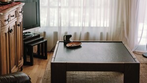 Uma sala de estar com televisão, mesa de centro e sofá.